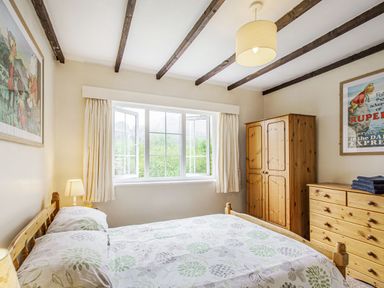 A bedroom with a wooden bed table lamp wooden wardrobe wooden chest of drawers and artwork on walls at Penlan in Beddgelert