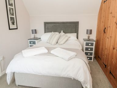 A bedroom with a double bed two bedside tables with lamps and wooden wardrobes at Cra-na-ge in Embleton