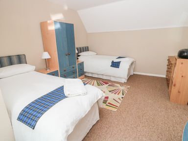 A bedroom with two single beds a wardrobe a chest of drawers and a small rug on the floor at Cra-na-ge in Embleton