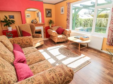 A living room with patterned sofa and armchairs a coffee table and a large window at Cra-na-ge in Embleton