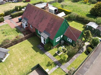 An aerial view of a green and brick house with a tiled roof surrounded by grass and garden sheds at Cra-na-ge Embleton