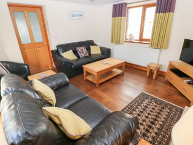 A living room with a sofa and coffee table at Bwthyn Trecoed St. Clears near Carmarthen