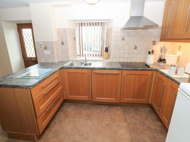 A kitchen with wooden cabinets and a sink at Bwthyn Trecoed St. Clears near Carmarthen