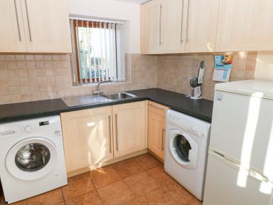A kitchen with a washing machine and refrigerator at Bwthyn Trecoed in St. Clears near Carmarthen