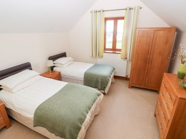 A bedroom with two single beds and wooden furniture at Bwthyn Trecoed St. Clears near Carmarthen