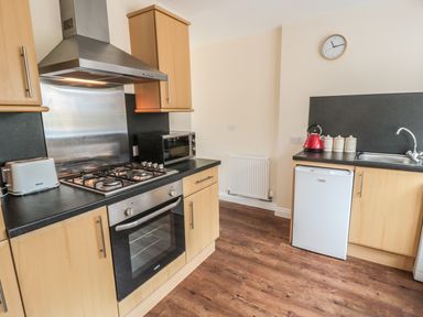 A kitchen with a stove oven toaster microwave red kettle and sink at No 1 Low Hall Cottages Scalby near Scarborough
