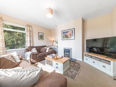 A living room with brown sofas a wooden coffee table and a television at Colt Park Cottage in Ulverston