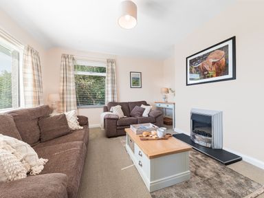 A living room with brown sofas a coffee table and a fireplace at Colt Park Cottage in Ulverston