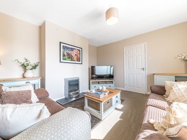 A living room with two sofas a coffee table a television and a fireplace at Colt Park Cottage in Ulverston