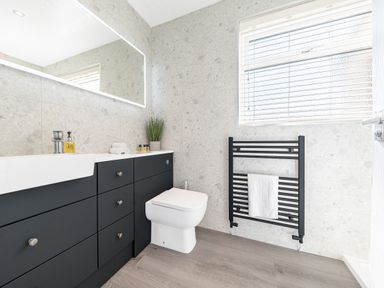 A bathroom with a black vanity unit with a sink a toilet a black towel radiator a window with blinds and a large mirror at Colt Park Cottage in Ulverston