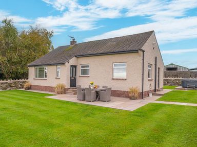 Exterior view of a single-story house with patio furniture on a lawn at Colt Park Cottage in Ulverston
