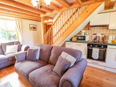 A living room with sofas near a staircase and kitchen appliances at Moorgair Cottage Slaley near Hexham