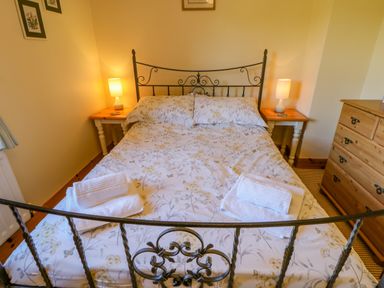 A bedroom with a double bed with floral bedding and folded towels on it at Moorgair Cottage Slaley near Hexham