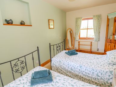 A bedroom with two single beds with floral bedding and towels on them at Moorgair Cottage in Slaley near Hexham