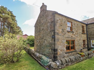 A stone cottage with wooden windows and a stone wall in a garden at Moorgair Cottage in Slaley near Hexham