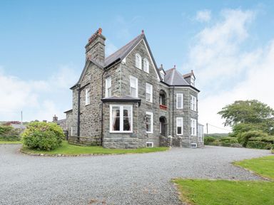A large stone house with multiple windows and a gravel driveway at Pensarn Hall in Llanbedr near Harlech