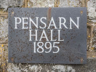A metal plaque on a stone wall with the text Pensarn Hall 1895 at Pensarn Hall in Llanbedr near Harlech