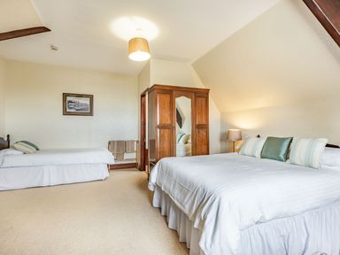 A bedroom with a double bed and a single bed a wooden wardrobe and a lamp at Pensarn Hall in Llanbedr near Harlech