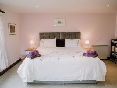A bedroom with a large bed with floral bedding and purple towels on top at Stargazer's Field House in Hardwicke near Hay-on-Wye