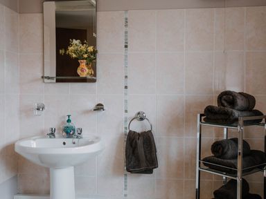 A bathroom with a sink and mirror with towels on a rack at Stargazer's Field House in Hardwicke near Hay-on-Wye