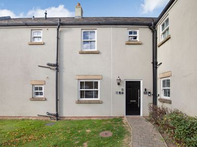 The front exterior of a house with a black door and white framed windows at Perriwinkle The Bay near Filey