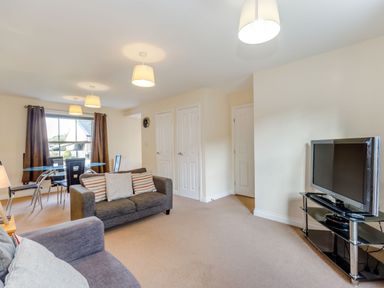 A living room with two sofas a glass dining table with chairs and a television on a stand at Perriwinkle The Bay near Filey
