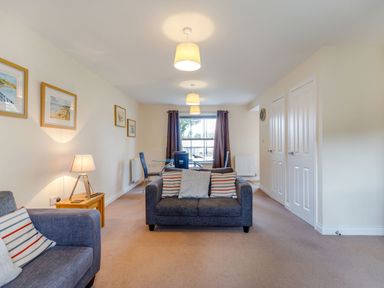 A living room with two sofas a glass dining table chairs and framed pictures on the wall at Perriwinkle The Bay near Filey