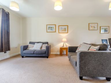A living room with two grey sofas a wooden side table with a lamp and framed pictures on a wall at Perriwinkle in The Bay near Filey