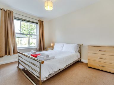 A bedroom with a double bed bedside table with lamp chest of drawers and window with curtains at Perriwinkle The Bay near Filey