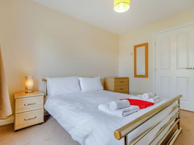 A bedroom with a double bed bedside table with a lamp and chest of drawers at Perriwinkle The Bay near Filey