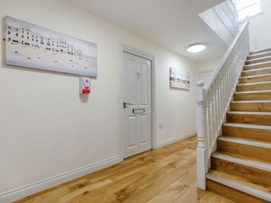 A hallway with wooden flooring stairs and white doors at Perriwinkle The Bay near Filey