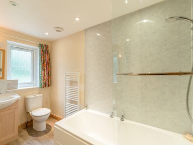 A bathroom with a bathtub shower toilet sink and heating rack at Stephens Cottage in Alnmouth