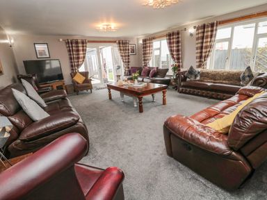 A living room with leather sofas cushions a wooden coffee table and a television at On The Watersedge in Beadnell