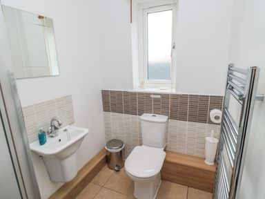 A bathroom with a toilet sink trash can and a towel radiator at On The Watersedge in Beadnell