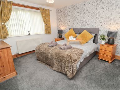 A bedroom with a double bed bedside tables and a window at On The Watersedge in Beadnell