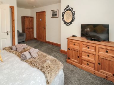 A bedroom with a bed and towels a wooden dresser with a television and a decorative mirror at On The Watersedge in Beadnell
