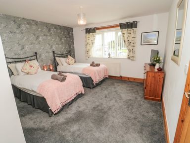 A bedroom with two single beds a dresser and a window with curtains at On The Watersedge in Beadnell