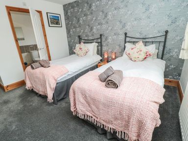 A bedroom with two single beds and floral pillows at On The Watersedge in Beadnell