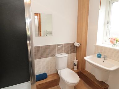 A bathroom with a toilet sink mirror and window at On The Watersedge in Beadnell