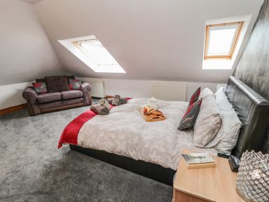 A bedroom with a bed with breakfast tray and a sofa under skylight windows at On The Watersedge in Beadnell