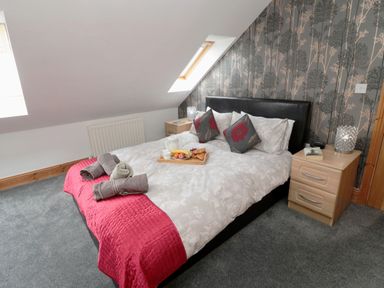 A bedroom with a double bed with white bedding and red blanket and two bedside tables with lamps at On The Watersedge in Beadnell