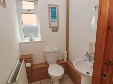 A bathroom with a toilet sink radiator window and wall decorations at On The Watersedge in Beadnell