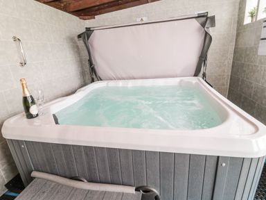 An indoor hot tub with water and a bottle of champagne with two glasses at On The Watersedge in Beadnell