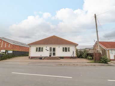 A single story house with red tiled roof and white walls facing a street at On The Watersedge in Beadnell