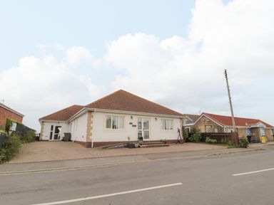 A single story house with a tiled roof and driveway on a road at On The Watersedge in Beadnell