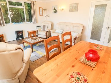 A living room with beige sofas a wooden dining table chairs and a coffee table at The Shack in Mawgan Porth near Newquay