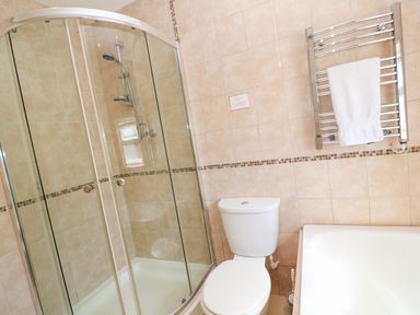 A bathroom with a glass shower enclosure a toilet a bathtub and a towel rack with a white towel at The Shack in Mawgan Porth near Newquay