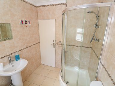 A bathroom with a shower enclosure a sink with soap and a wall mirror at The Shack in Mawgan Porth near Newquay