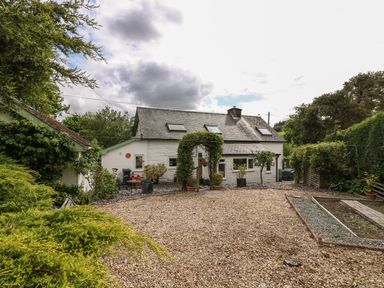 A gravel driveway and a small white house with skylights and plants at Penlone Cottage in Rhayader