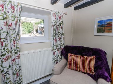 A snug with a window, radiator and armchair at Penlone Cottage Rhayader